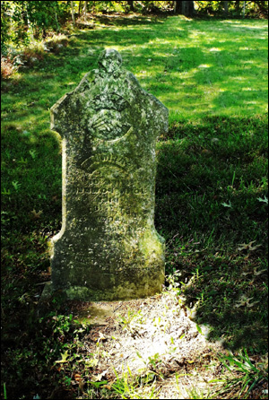 Picture of a grave with an old tombstone covered in moss.